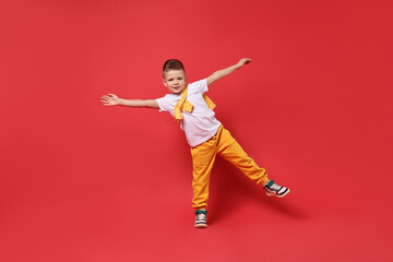 Happy little boy dancing on red background