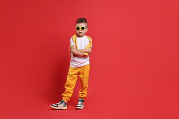 Fototapeta premium Happy little boy dancing on red background. Space for text