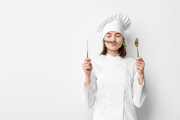 Professional chef with rosemary and cutlery having fun on light background. Space for text