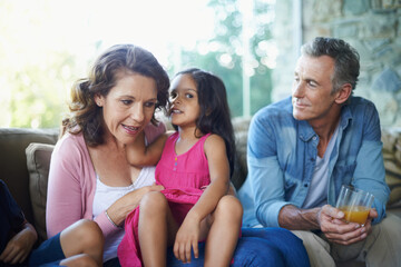 Obraz premium Whisper, bonding and happy family on sofa for conversation, secret or gossip talking. Smile, house and grandmother, grandfather and child on couch for comfort, care and joke together in home lounge