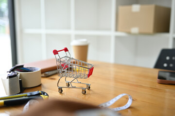 Shopping cart on wooden table in the warehouse. E-commerce, online shopping and small business...