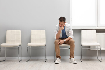 Man sitting on chair and waiting for appointment indoors