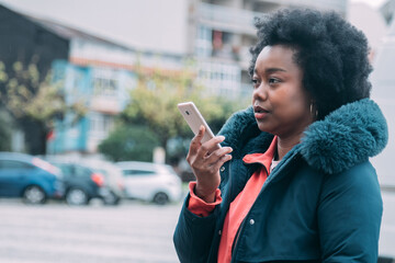 black woman sending an audio or voice message with phone on the street