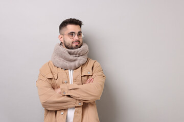 Smiling man in warm scarf on light grey background. Space for text