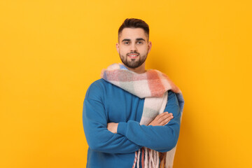 Smiling man in warm scarf on yellow background