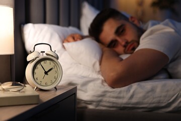 Frustrated man suffering from insomnia on bed, selective focus