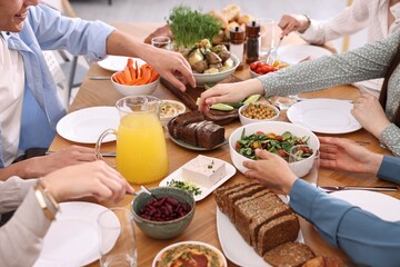 Friends eating vegetarian food at wooden table indoors, closeup