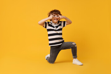 Happy little boy dancing on yellow background. Space for text