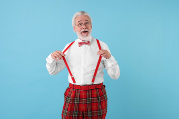 Portrait of stylish grandpa with glasses and bowtie on light blue background