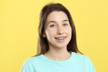 Portrait of smiling woman with dental braces on yellow background