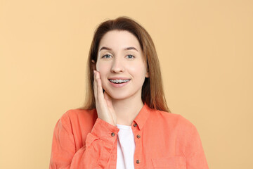 Fototapeta premium Portrait of smiling woman with dental braces on beige background