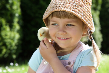 Cute little girl with chick outdoors. Baby animal © New Africa
