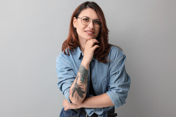 Portrait of beautiful tattooed woman on gray background