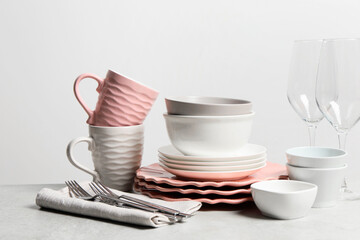 Beautiful ceramic dishware, cups, glasses and cutlery on light grey table