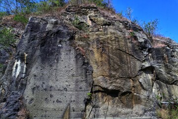 The cliff rock has trees with a blue sky background.
