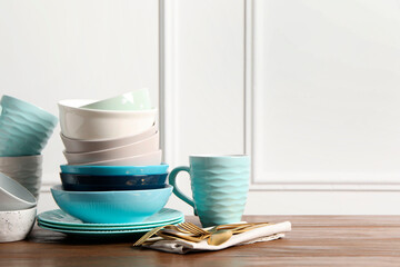Beautiful ceramic dishware, cup and cutlery on wooden table, space for text