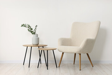 Comfortable armchair, nesting tables and eucalyptus indoors