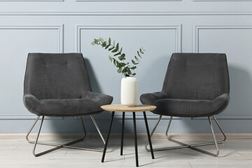 Comfortable armchairs, side table and eucalyptus indoors