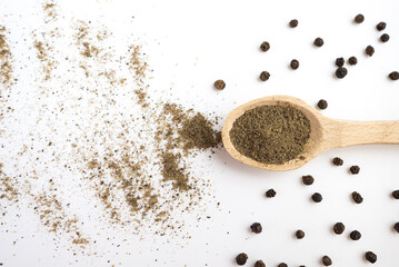  spoon with ground black pepper and peppercorns on a white background