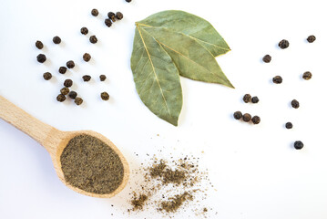 dried bay leaf and black pepper on a white background.