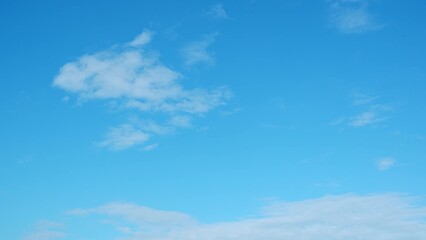 A vast blue sky with minimal cloud cover. A few small, white clouds are scattered across the sky,...