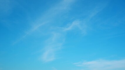 A vibrant blue sky with thin, wispy clouds scattered across it. The light clouds add texture and...