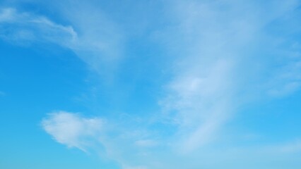 A bright blue sky with wisps of white clouds gently scattered across. The vibrant blue of the sky...