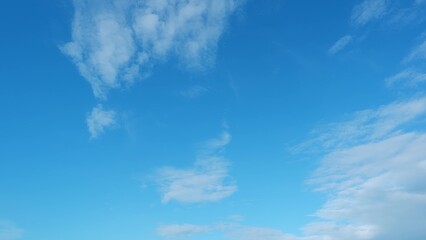 A bright blue sky with scattered, wispy clouds. The clouds form light, airy patterns against the...