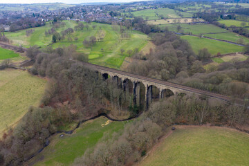 Naklejka premium Aerial drone photo across the village of Lightcliffe in Halifax in West Yorkshire in the UK, showing the fields along side a train track viaduct, taken on a cold day in the winter time.