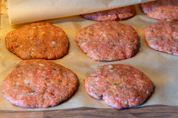 tray of meat patties are being cooked on a wooden table