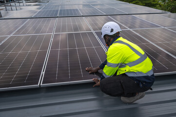 Black male solar engineer working with solar panels  on building roof
