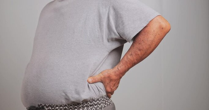 An old Asian man has back pain after lifting a heavy object.