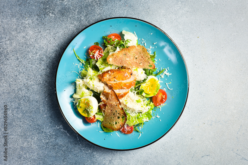 Wall mural fresh vegetable salad with chicken fillet and egg. traditional caesar salad. in a blue plate.