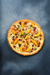 Bavarian pizza with smoked sausages, tomatoes, cheese, salt and spices on a dark concrete background