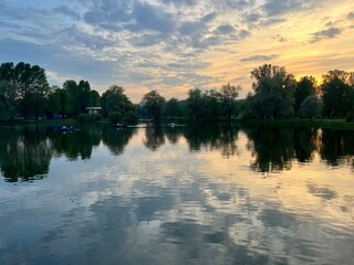 beautiful evening sky with clouds reflection on the lake surface, lake in the park, summer, trees silhouettes reflection