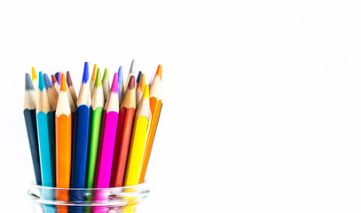 Fototapeta premium A vibrant collection of colored pencils arranged in a glass jar against a white background with copy space. Concept for back to school and creativity-themed content.