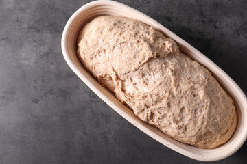 Fresh sourdough in proofing basket on grey table, top view. Space for text