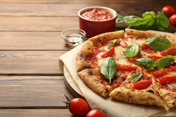 Delicious Margherita pizza and ingredients on wooden table, space for text