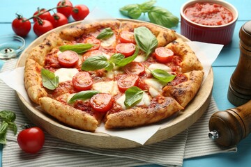 Delicious Margherita pizza and ingredients on light blue wooden table
