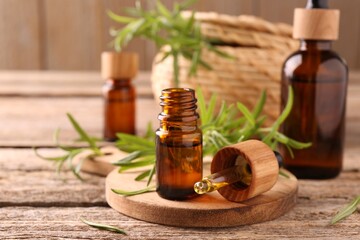 Aromatic essential oils in bottles, pipette and rosemary on wooden table, closeup