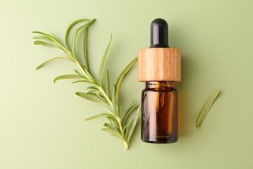 Aromatic essential oil in bottle and rosemary on green background, flat lay