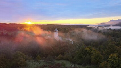 Aerial cinematic fairy tale castle with morning mystic sunrise and fog and smoke around the...