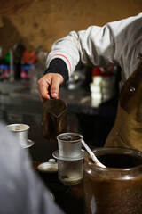 Barista pouring hot water into Vietnamese black coffee filter