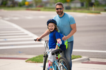 Father teaching son riding bike. Dad helping child son to ride a bicycle in american neighborhood....