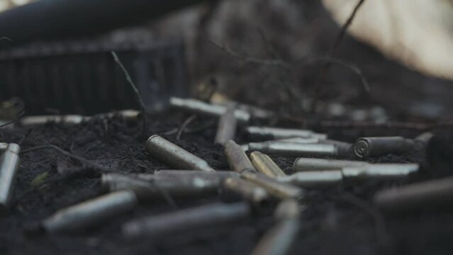 Cinematic slow motion footage spent bullet casings falling on the forest floor. World war one