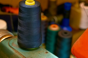 A spool of black thread on an old sewing machine in a tailor's workshop