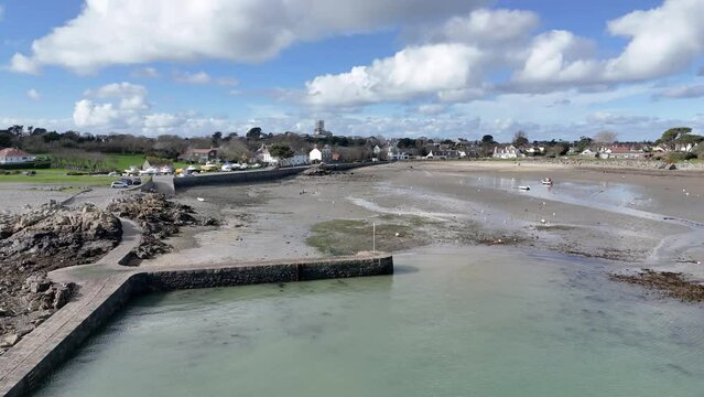 Bordeaux Harbour Guernsey low circling drone shot showing whole harbour on sunny day with boats on hardstanding and drying out and views over beach and towards the north of Guernsey