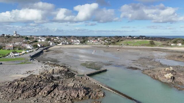 Bordeaux Harbour Guernsey high distant circling drone shot showing whole harbour on sunny day with boats on hardstanding and drying out and views over beach and towards the north of Guernsey