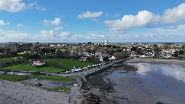 Bordeaux Harbour Guernsey high circling drone shot on sunny day with boats on hardstanding and views over beach to St Sampsons