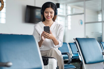 Woman listening to music on headphones in airport lounge, use smartphone and earphones while waiting for her flight